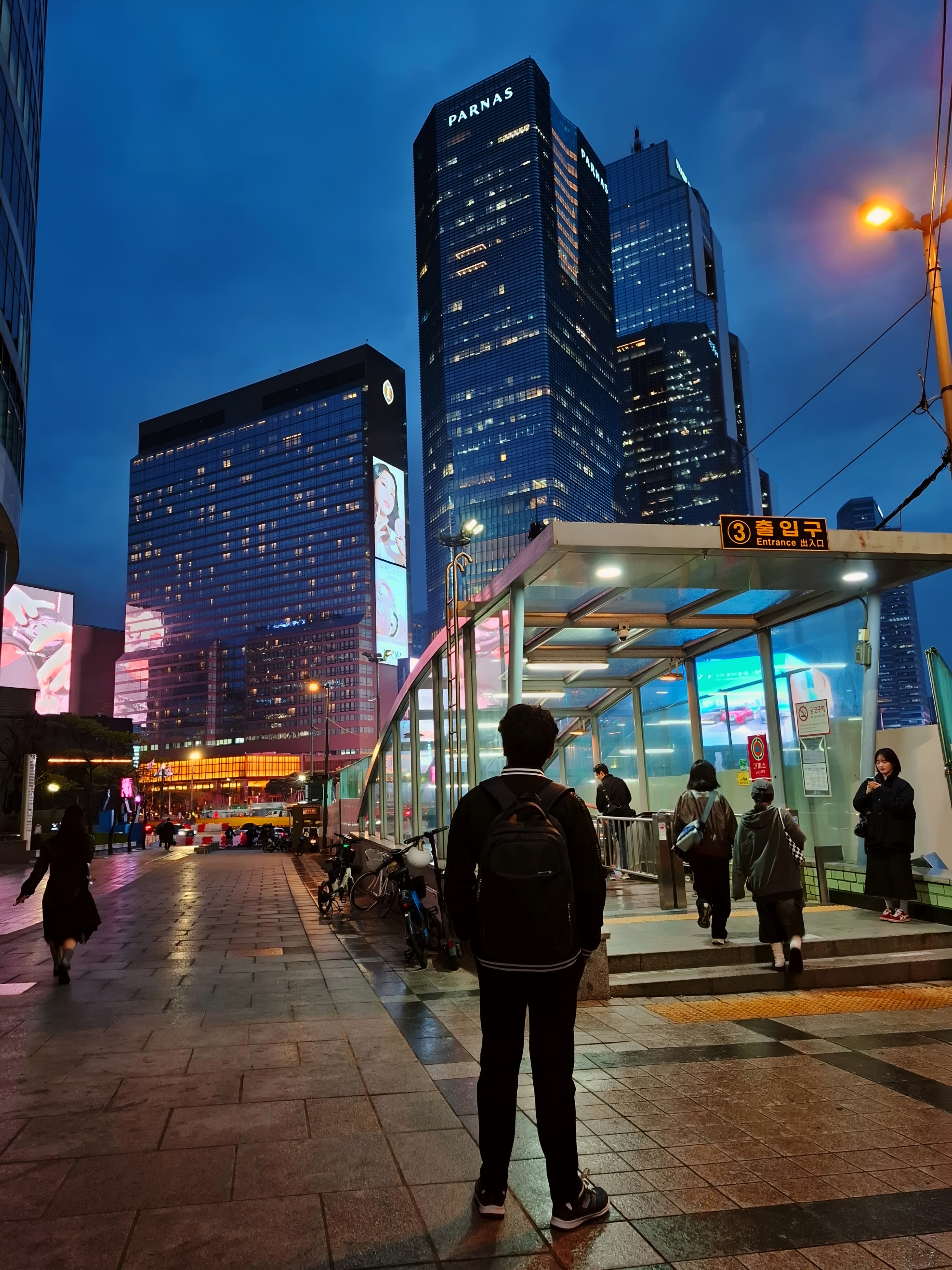 Shawkat Hossain Maruf looking at the towering illuminated skyscrapers near COEX Square and Samseong Station in Gangnam, Seoul at night.